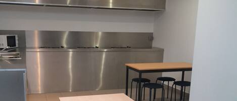 A modern kitchen with stainless steel appliances, a wooden table, and four chairs.
