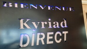 Een bord met verlichte letters waarop 'BIENVENUE' en 'Kyriad DIRECT' staan.