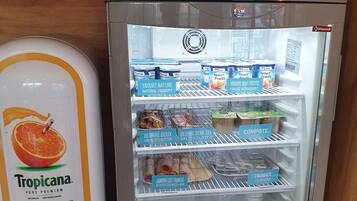 A refrigerator stocked with various food items including natural yogurt, unsalted butter, and sliced cooked ham.