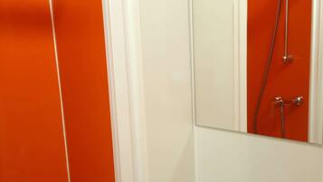Een badkamer met een witte wastafel, een spiegel en een douche met een chroomdouchekop.