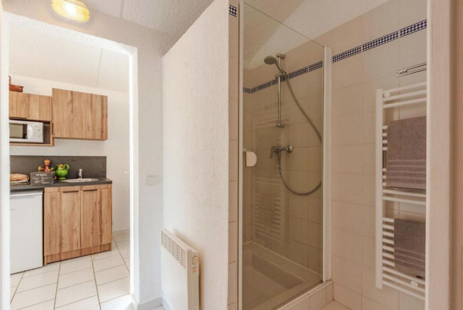 A modern bathroom with a glass shower enclosure, a white tiled shower area, and a built-in towel rack.