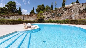 A swimming pool with lounge chairs and a clear view of the surrounding landscape.
