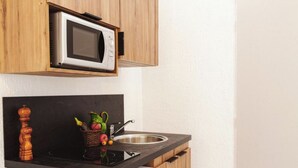 A compact kitchen with a microwave, sink, and wooden cabinets.