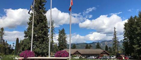 A golf club sign with flags, a mountain backdrop, and a building with a roof.