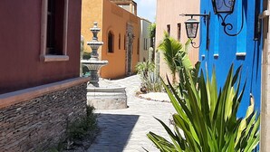 A narrow cobblestone street flanked by buildings with stone and stucco exteriors.