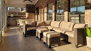 En overdækket terrasse med en hjørnesofa, fletmøbler og en loftventilator.