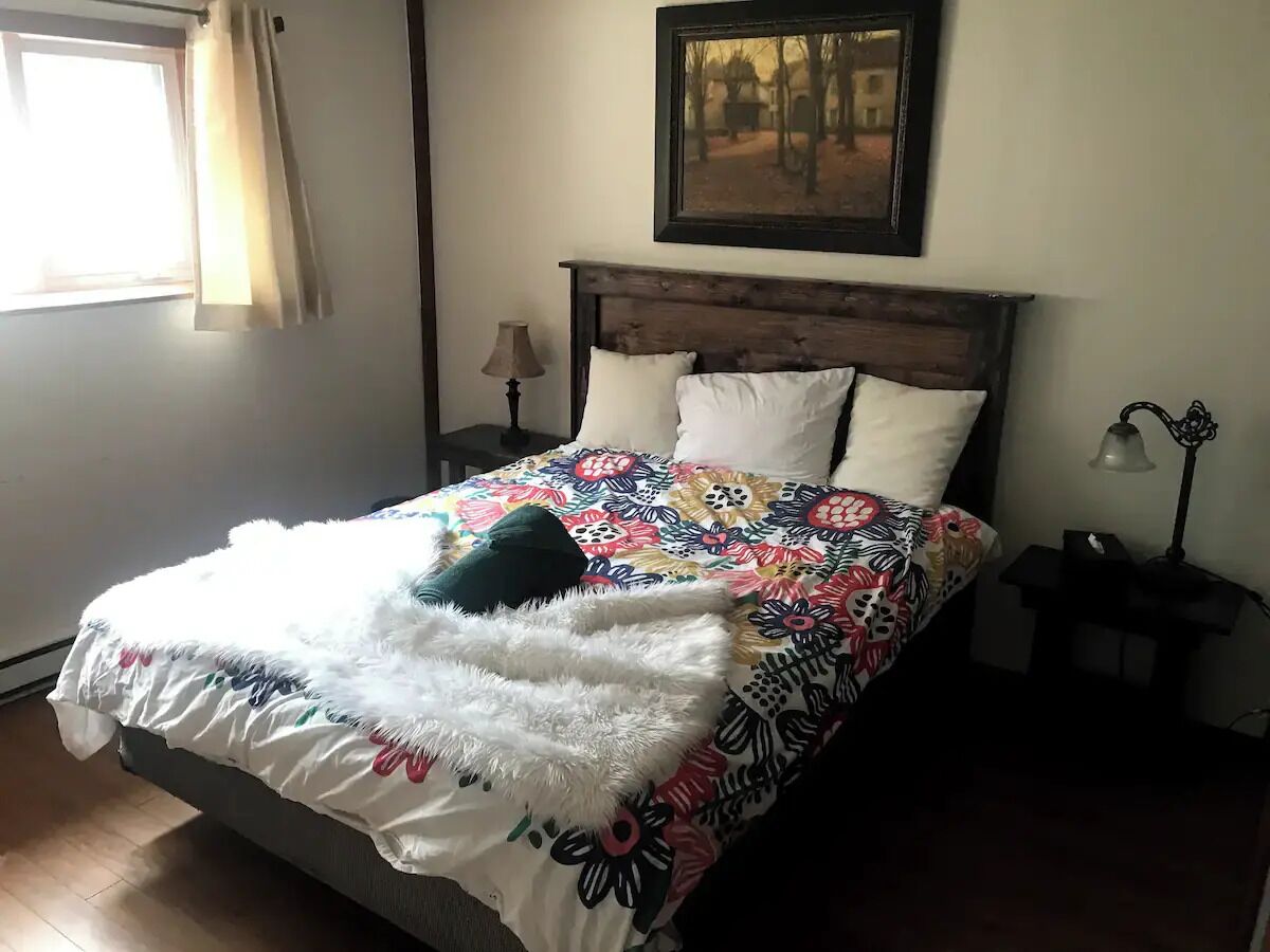 Una cama con una colcha estampada con flores, una manta suave y mullida, y dos almohadas.