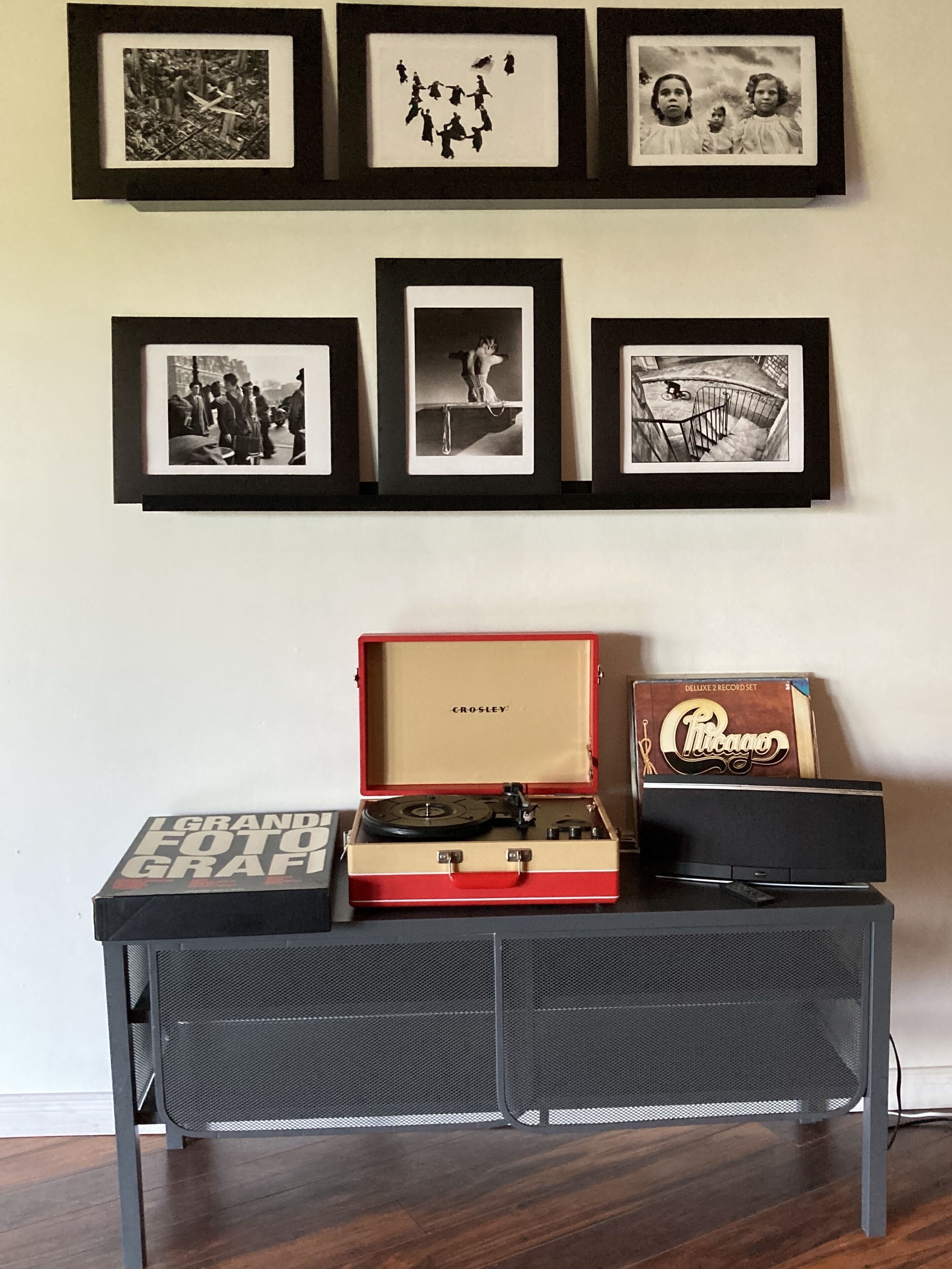 Una pared con fotografías enmarcadas y un tocadiscos sobre un escritorio.