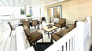 An outdoor patio with a table and chairs, a sliding glass door, and a white railing.