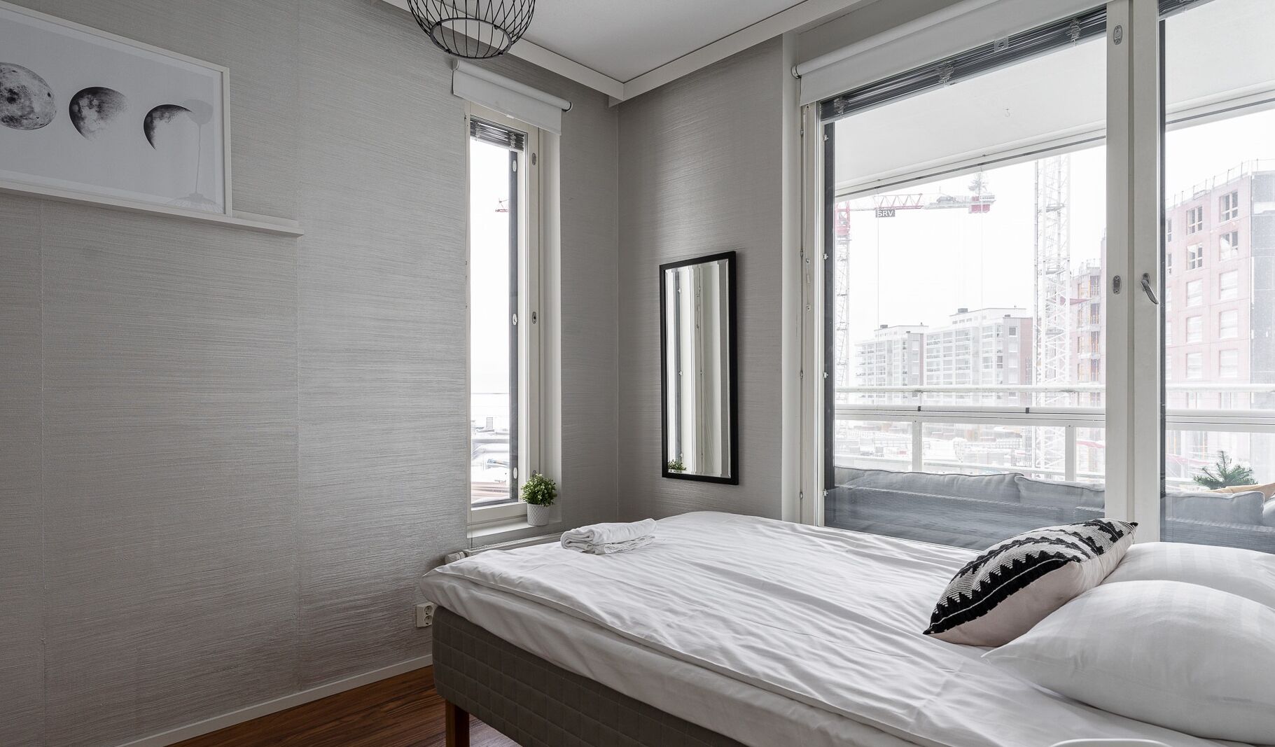 Ein Schlafzimmer mit Bett, Fenster, Spiegel und einem Wandbild der Mondphasen.