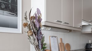 Una cocina moderna con armarios blancos, encimera de madera y una mesa de comedor con un florero.