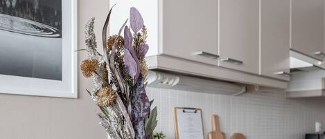A modern kitchen with white cabinets, a wooden countertop, and a dining table with a vase of flowers.
