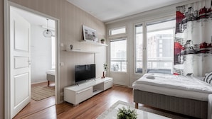 Una sala de estar moderna con una televisión de pantalla plana, un sofá, una mesa de centro y un ventanal con vistas a la ciudad.