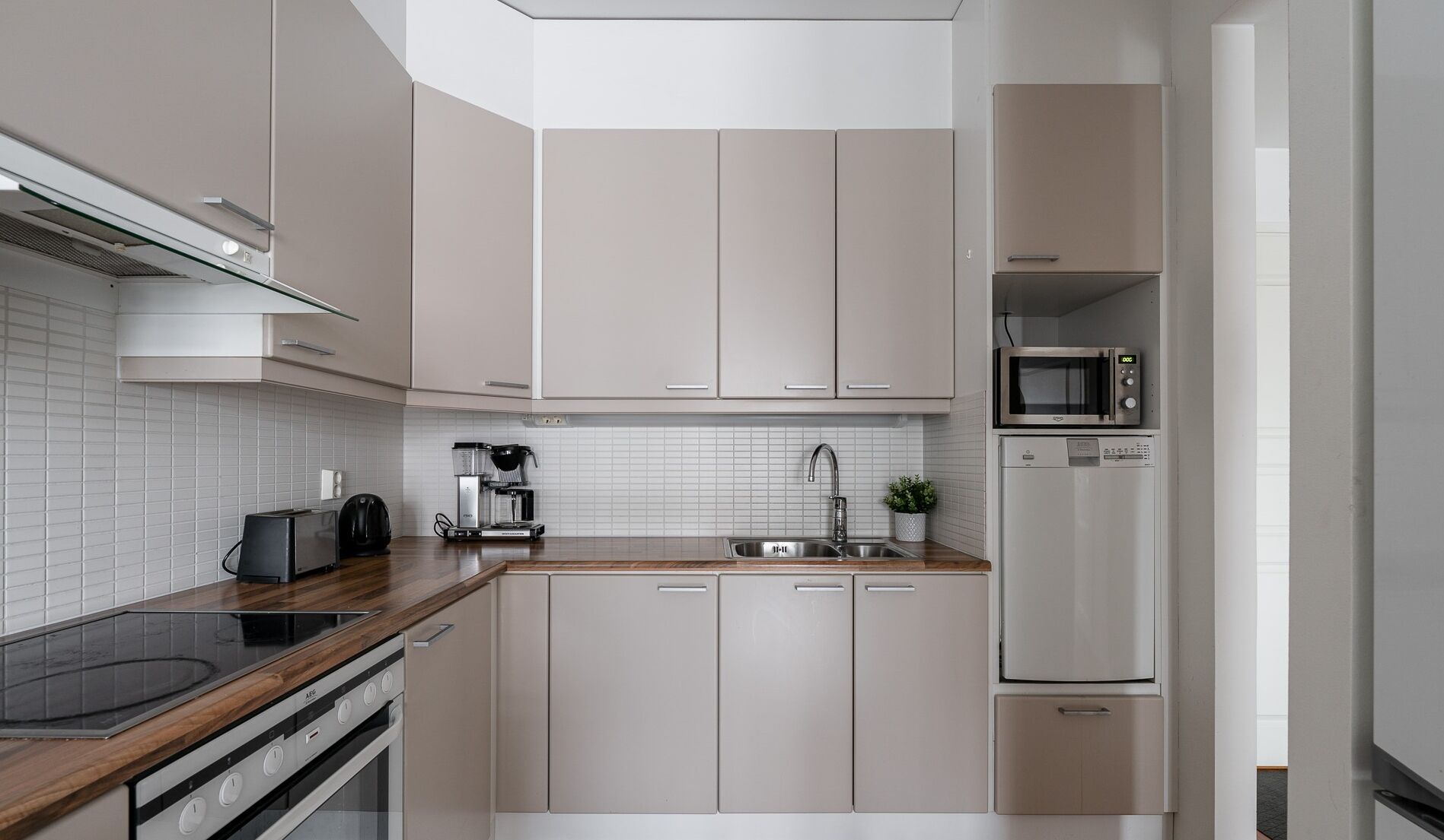 A modern kitchen with a built-in stove, a coffee maker, a microwave, and a refrigerator.