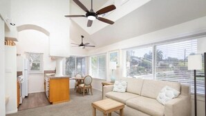 Un vaste espace de vie comprenant un canapé beige, une table basse en bois et un ventilateur de plafond.