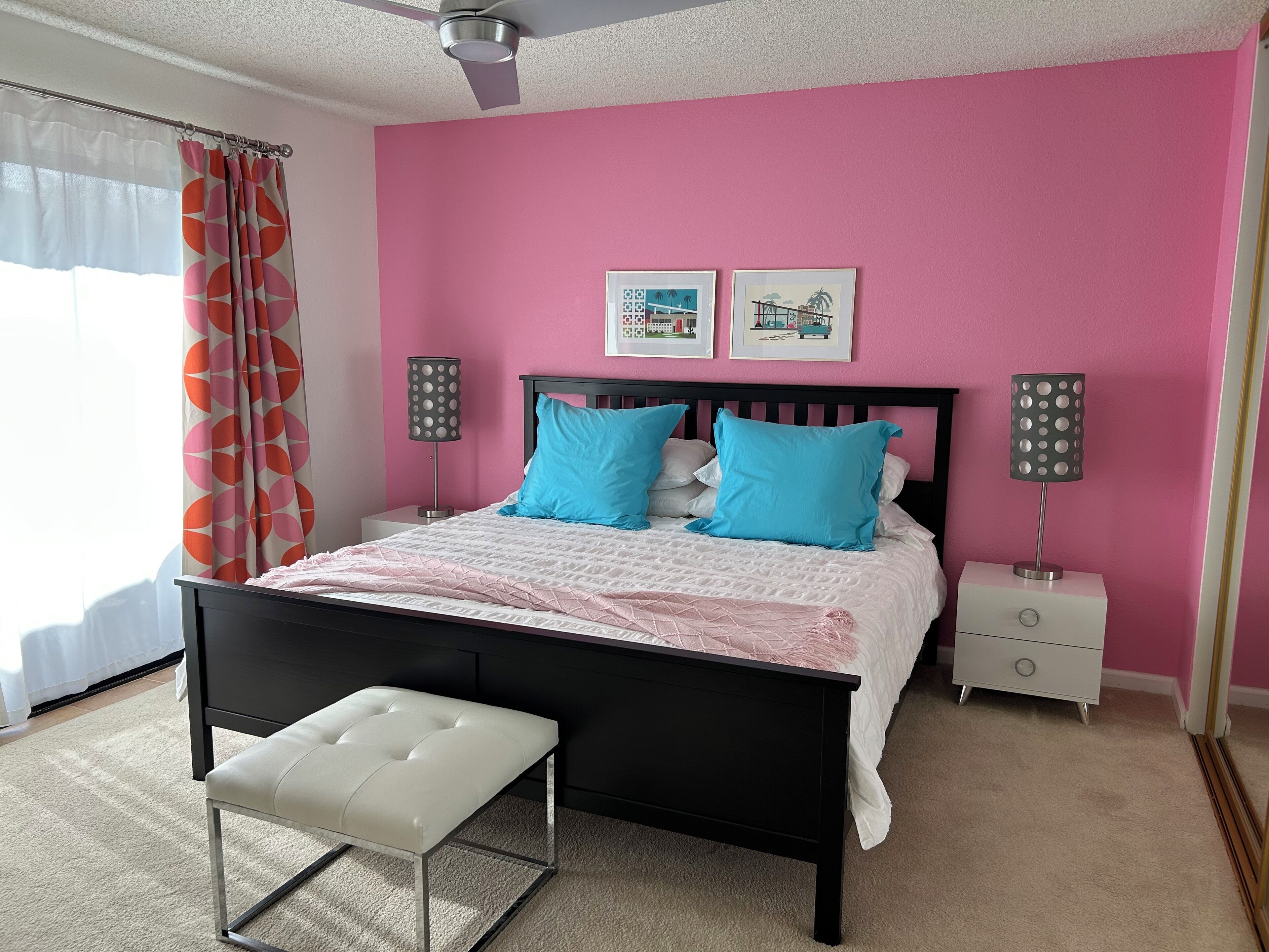 A bedroom with a bed, two bedside tables, a bench, and a ceiling fan.