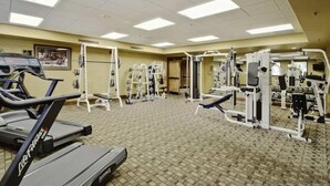 A gym with treadmills, weight machines, and a mirrored wall.