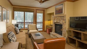 A cozy living room with a stone fireplace, a television, and a sofa.