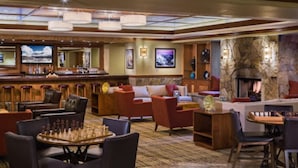 A hotel lobby with a bar, seating areas, a fireplace, and a television.