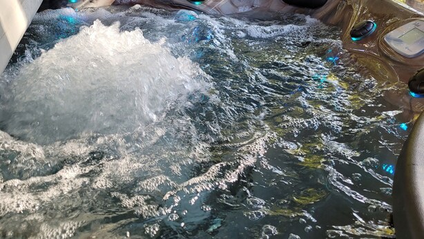 A hot tub with water jets, surrounded by outdoor seating and trees. - Spacious 4 bedroom, 3 bath home with hot tub and mountain views.  (Luray)