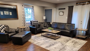 A modern living room with a sectional sofa, a coffee table, and a rug. - Spacious 4 bedroom, 3 bath home with hot tub and mountain views.  (Luray)