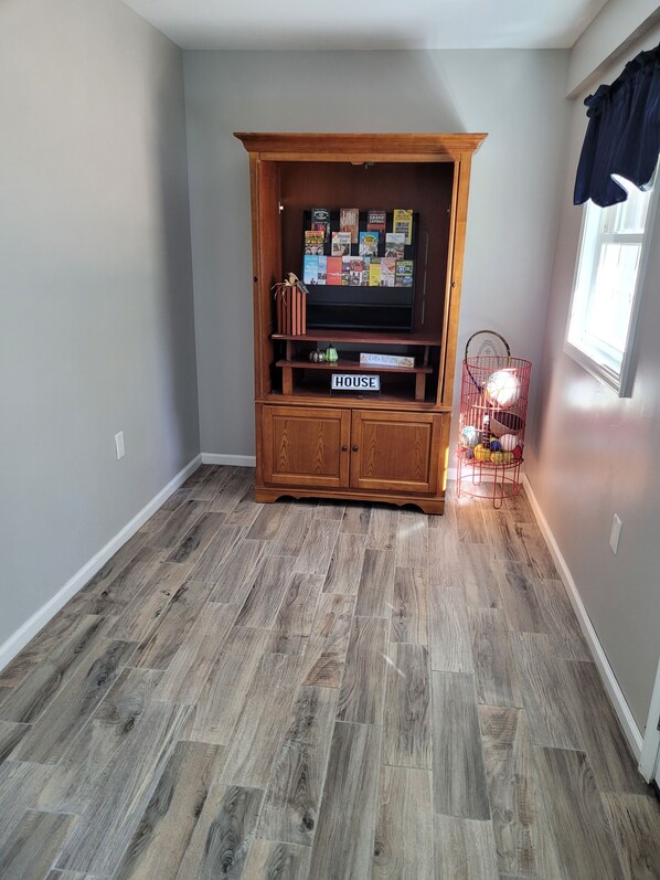 A room with a wooden entertainment center, a sign labeled 'HOUSE,' and a window with curtains. - Spacious 4 bedroom, 3 bath home with hot tub and mountain views. (Luray)