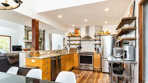 Una cocina moderna con armarios de madera, electrodomésticos de acero inoxidable y un comedor con mesa y sillas.