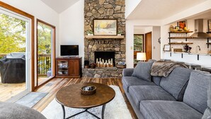 Una sala de estar moderna con chimenea de piedra, un sofá gris y un televisor.