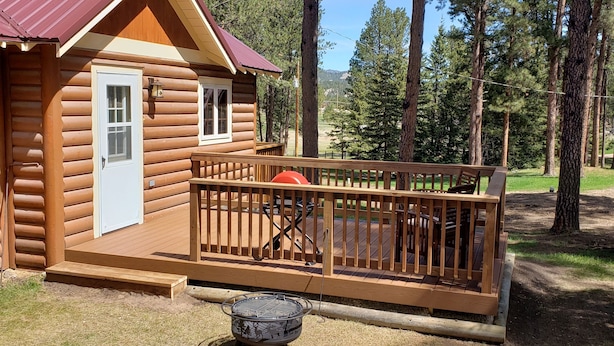 Eine Blockhütte mit einer Veranda, einem Grill und einer Tür.