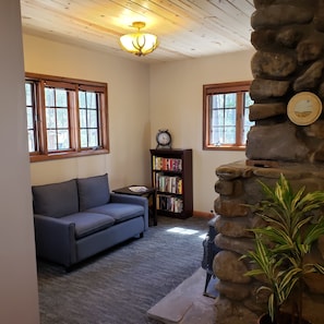 Sitting area with stone, wood burning  fireplace and books. Operable windows. 