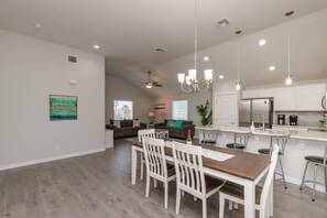 A spacious kitchen with white cabinetry, a central island, and pendant lighting.
