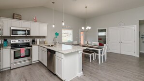 Une cuisine moderne avec des meubles blancs, une cuisinière en acier inoxydable et un grand îlot central doté d’un évier.