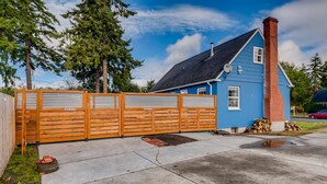 Een blauw huis met houten omheining, schoorsteen en oprit.