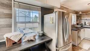 Een moderne keuken met een groot raam, roestvrijstalen apparatuur en een ingebouwde vaatwasser.