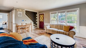 Een knus woongedeelte met een bank, een bijzettafeltje en een eethoek met een tafel en stoelen.