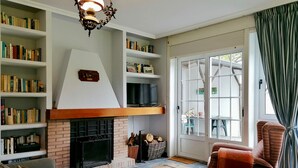 A cozy living room with a fireplace, bookshelves, a sofa, and a television.