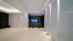 Un moderno vestíbulo de hotel con mostrador de recepción, zona de estar y una gran pantalla digital.