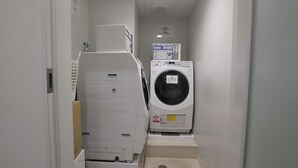 A laundry room with a front-loading washing machine and a dryer. - ibis Styles Tokyo Ginza (Tokyo)