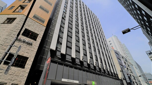 Un edificio de gran altura con un diseño arquitectónico moderno, que presenta una entrada destacada con un cartel que indica una altura libre de 2,9 metros.