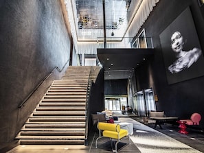 A modern interior with a staircase, seating area, and a large wall art piece.