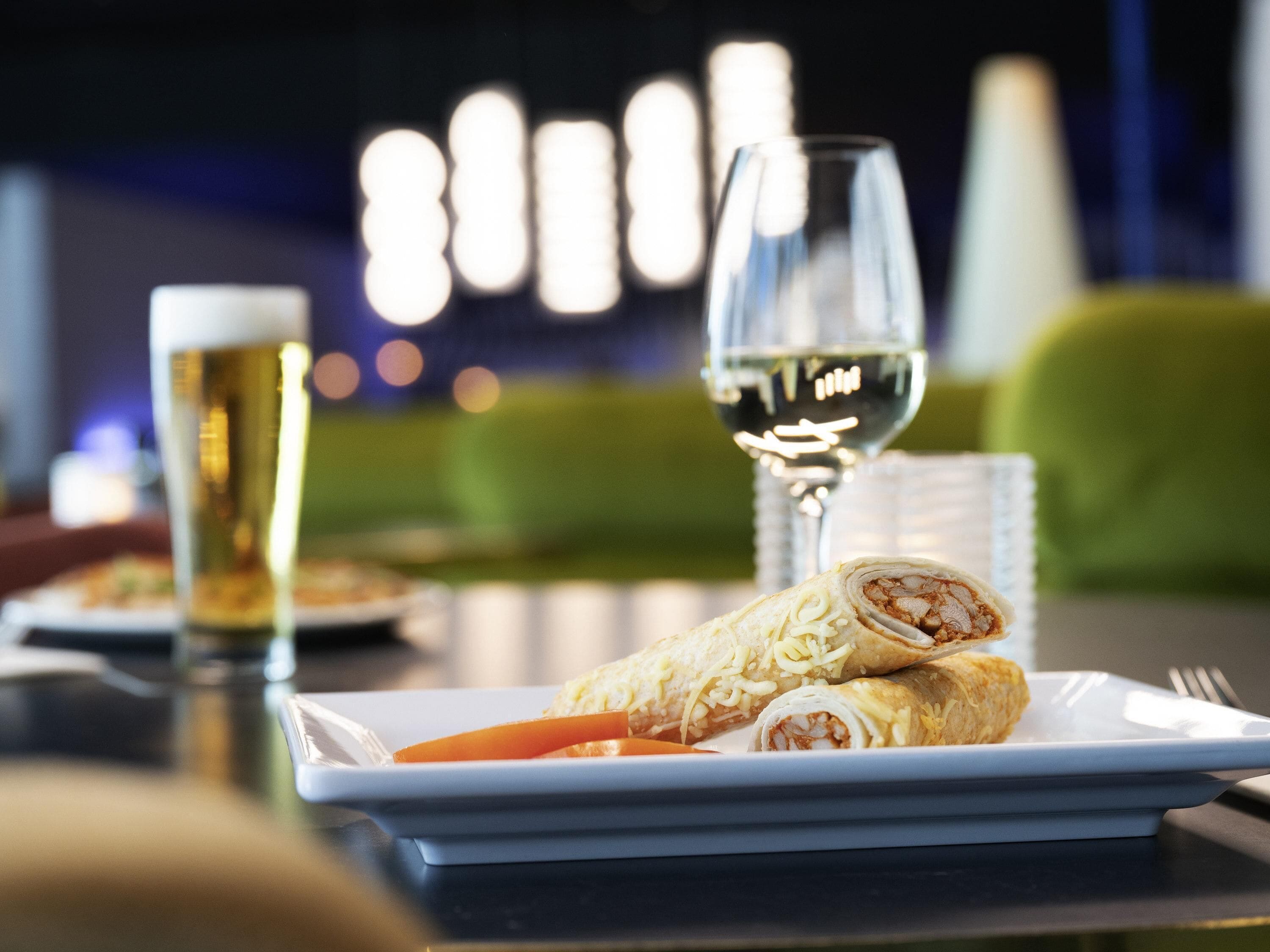 Een eettafel met een bord eten, een glas witte wijn en een glas bier.