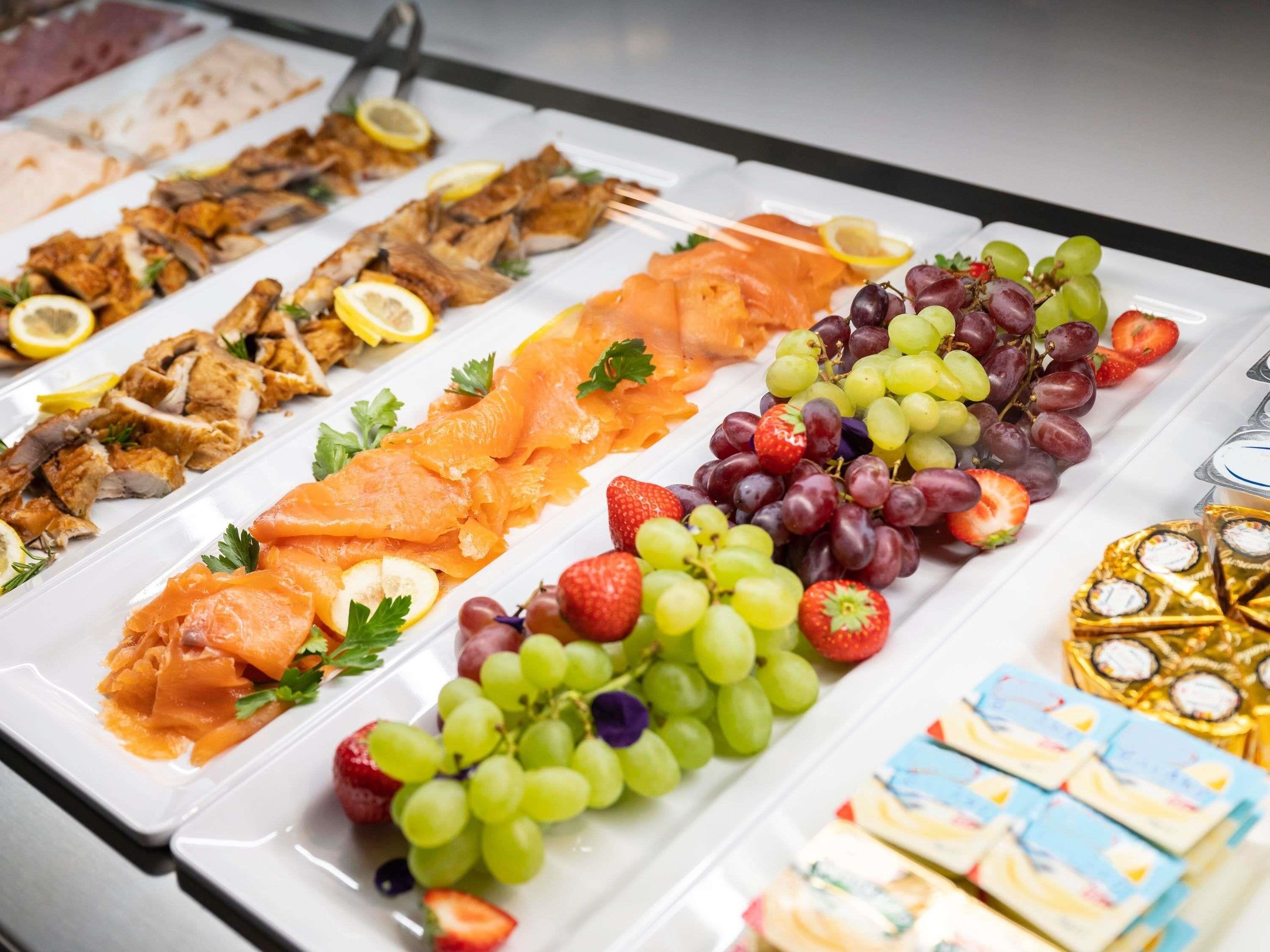 A buffet with various food items including salmon, chicken, and fruits.