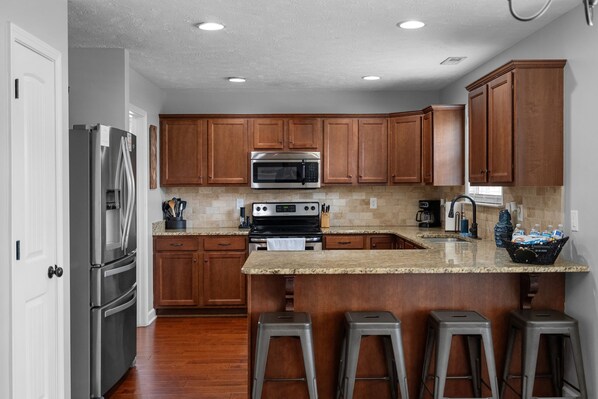 A modern kitchen with stainless steel appliances, wooden cabinets, and a granite countertop.