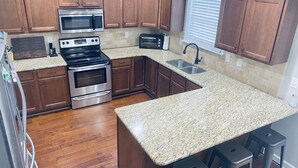 A kitchen with wooden cabinets, stainless steel appliances, granite countertops, and a window with blinds. - Quiet 4 bedroom villa with tons of space (Murfreesboro)