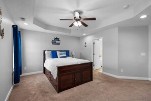 A bedroom with a bed, a ceiling fan, a wall-mounted anchor decoration, and a door.