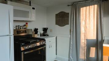 A compact kitchen with a stove, microwave, and cabinets.