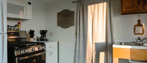 A compact kitchen with a stove, oven, microwave, and a small sink.