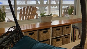 Een gezellige kamer met een rieten stoel, een blauw kussen en een houten tafel met planten in potten.