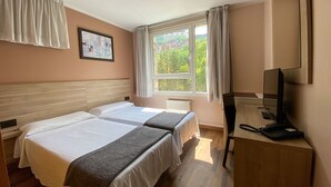 A hotel room with two beds, a desk with a computer and phone, a window with curtains, and a painting on the wall. - Somriu Vall Ski (Soldeu)