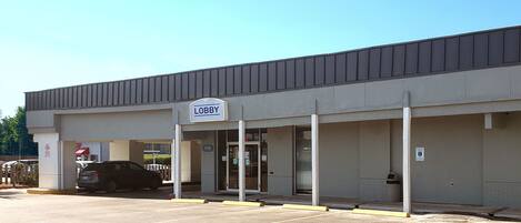 A building with a sign reading "LOBBY" and a parking lot in front.